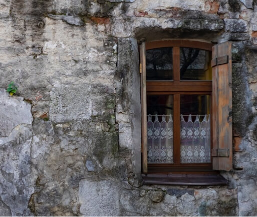 an old stone wall with a window with open wooden shutters